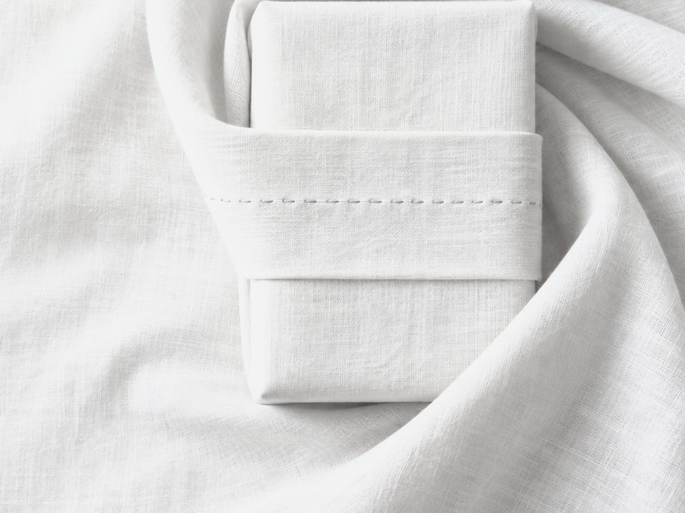 Folded white linen held by a stitched band